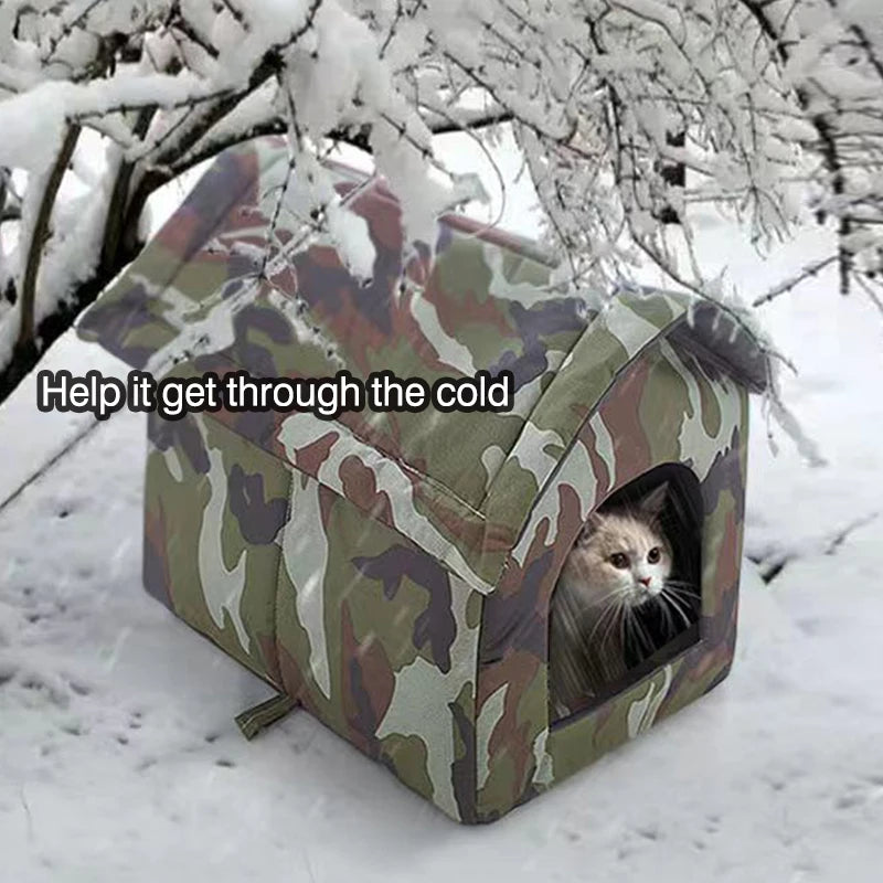 Camouflage cat house with a cat peeking out in a snowy landscape